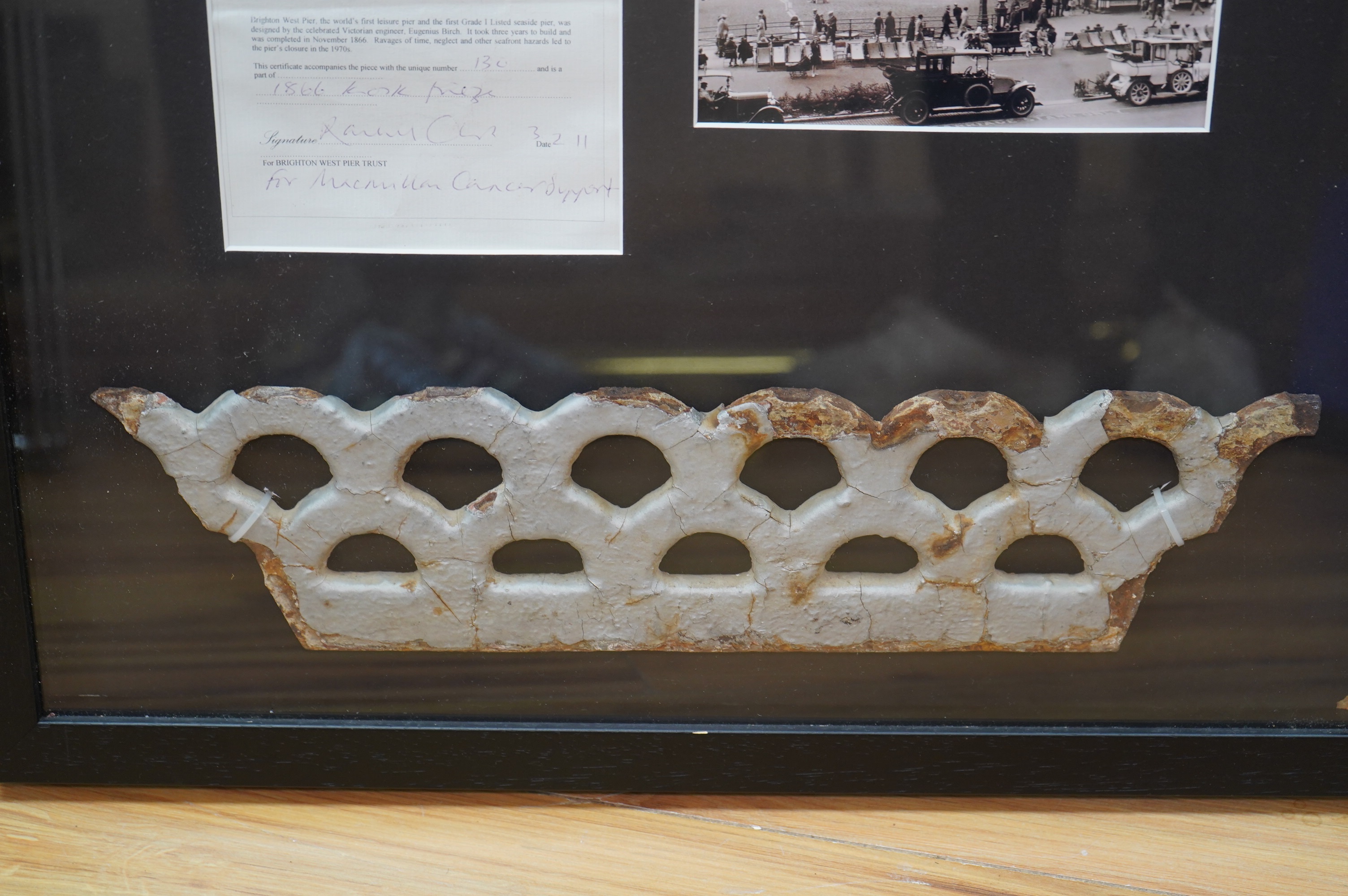 A framed part of the original frieze from the West Pier in Brighton, a photo and certificate, plus a book about the West Pier, 50cm wide, 40cm high. Condition - good